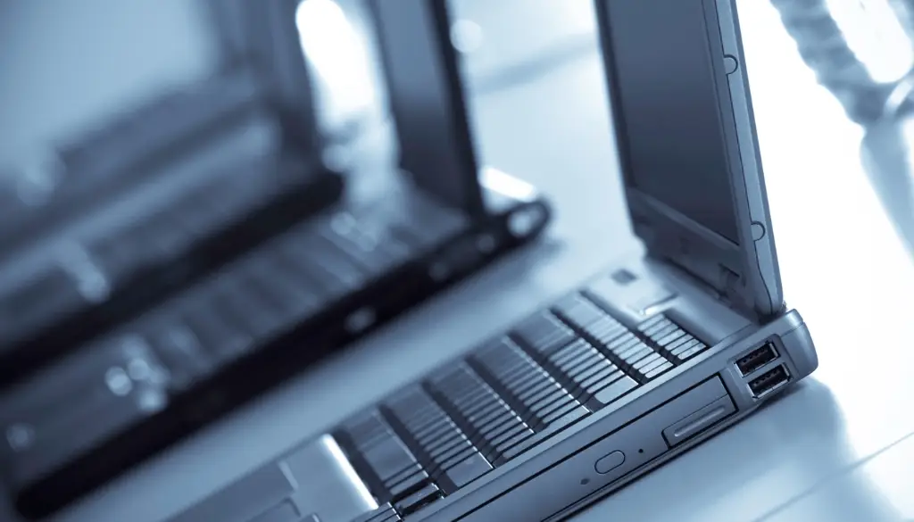 Company laptops lined up to be sent to a remote workforce.|Open laptops on a countertop ready for remote work.